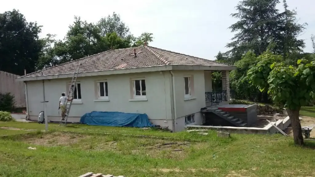Couvreur au pied d'une maison dont la toiture en tuiles va être reprise, dans le Tarn